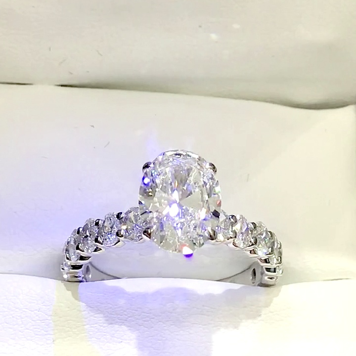 18kt White Gold Engagement Ring with 2.0 carat lab diamond at the center (Color: E | Clarity: VVS2 | Oval Cut) and natural E / VVS grade Setting Diamonds. Shared Prong Setting.
